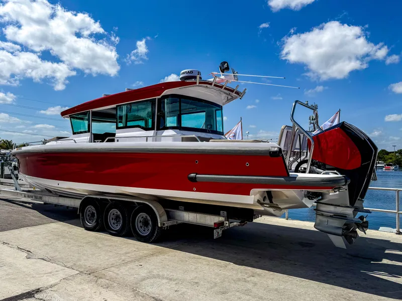 Slide: The Image of 2023 Axopar 37 XC CROSS CABIN boat on trailer, red and white design, sunny day. - 4