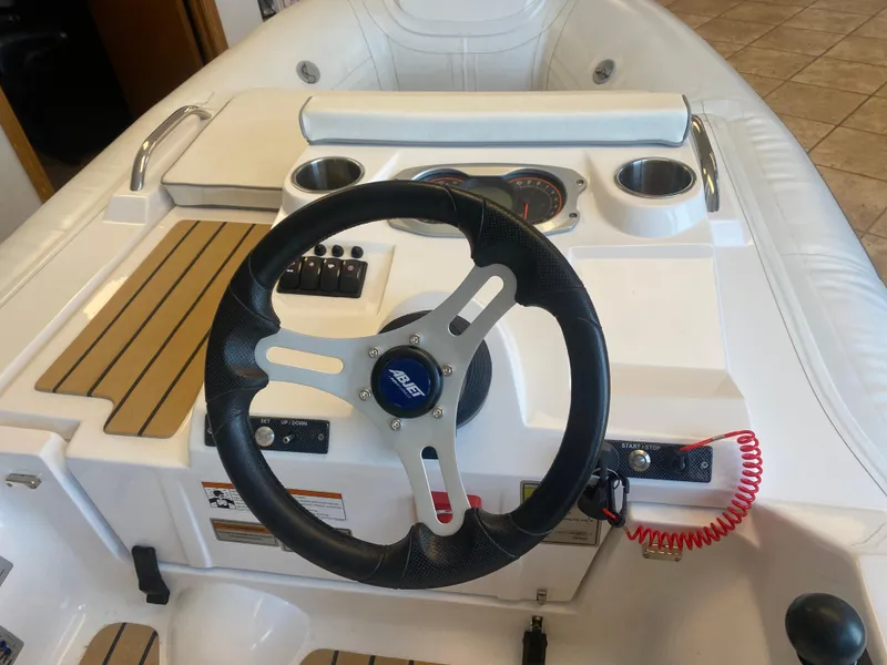 Slide: The Image of 2024 AB Inflatables ABJET 290 steering console with modern controls and cup holders. - 2