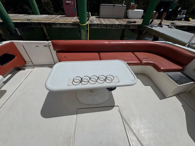 Slide: The Image of 1999 Sea Ray Sundancer 50 boat interior with red seating and table featuring a logo. - 11