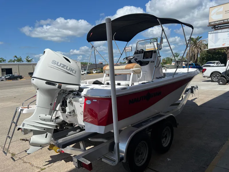 Slide: The Image of 2025 NauticStar 194 Bay boat with Suzuki engine on trailer, parked outdoors. - 3