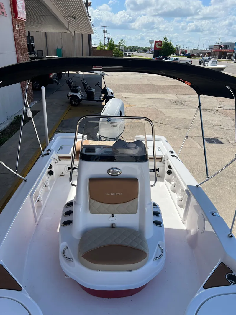 Slide: The Image of 2025 NauticStar 194 Bay boat with canopy, docked under a clear sky. - 5