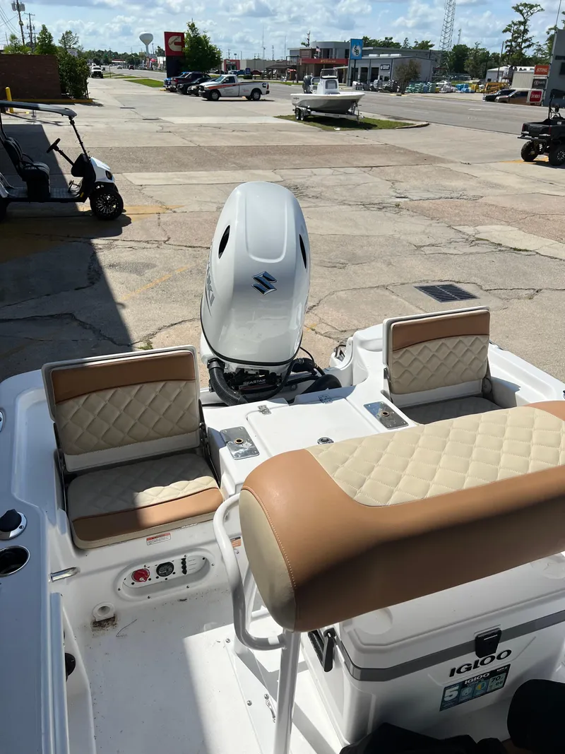 Slide: The Image of 2025 NauticStar 194 Bay boat interior with seating and motor, parked outdoors. - 7