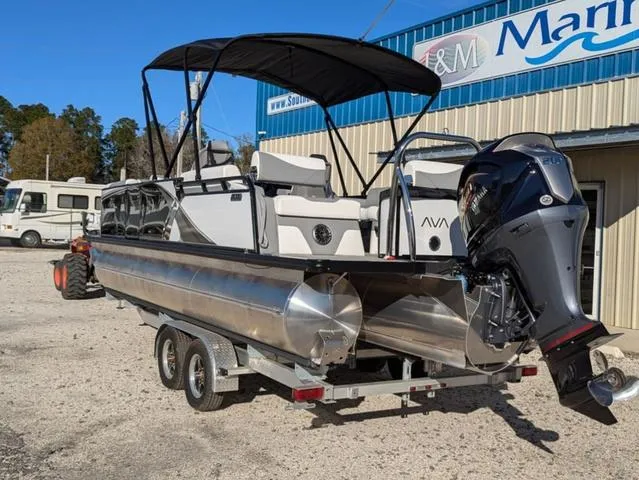 Slide: The Image of 2025 Avalon LSZ Quad Lounge Switch 2385 pontoon boat on trailer, parked outside a marina. - 5