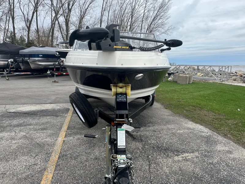 Slide: The Image of 2011 FinCraft 1850 boat on trailer, parked near a lake with overcast skies. - 2