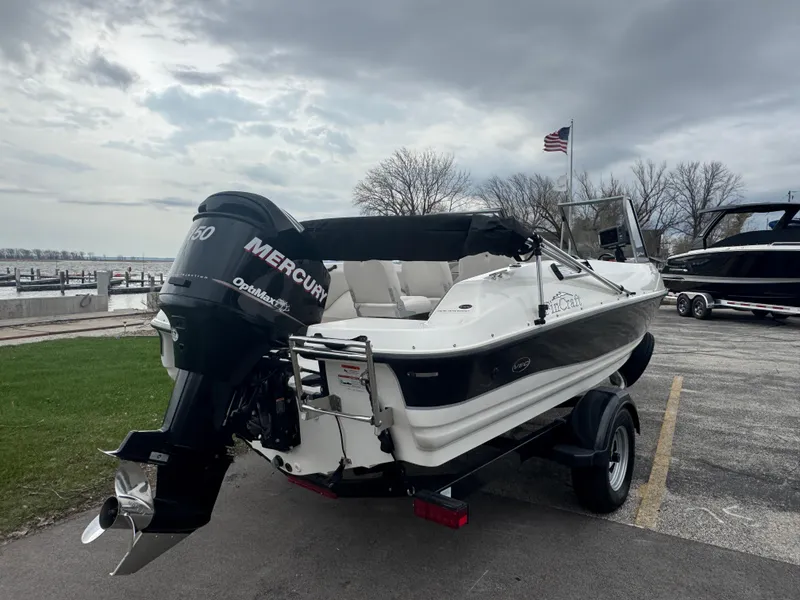 Slide: The Image of 2011 FinCraft 1850 boat with Mercury engine, parked near a lake under cloudy skies. - 5
