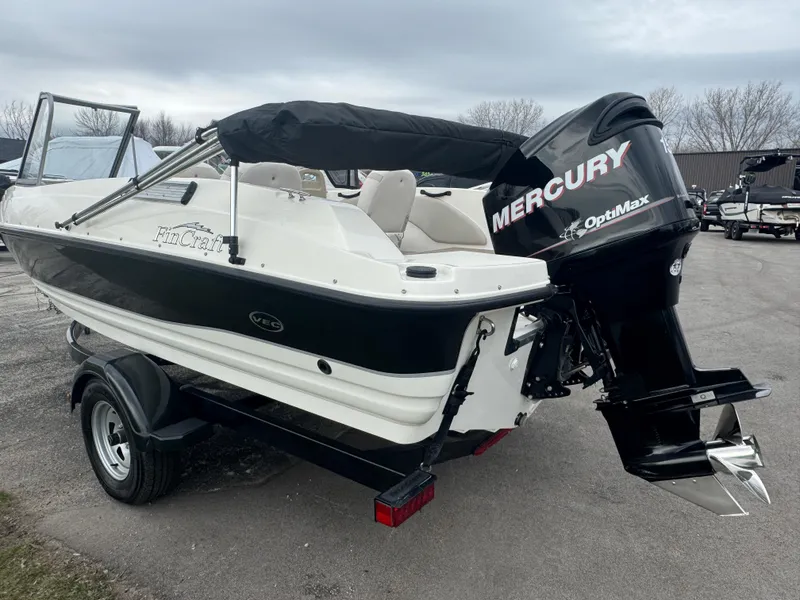 Slide: The Image of 2011 FinCraft 1850 boat with Mercury OptiMax engine on a trailer, parked outdoors. - 6