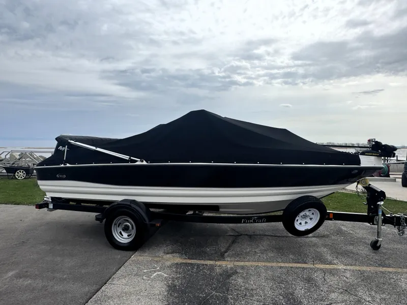 Slide: The Image of 2011 FinCraft 1850 boat on trailer with black cover, parked outdoors. - 8