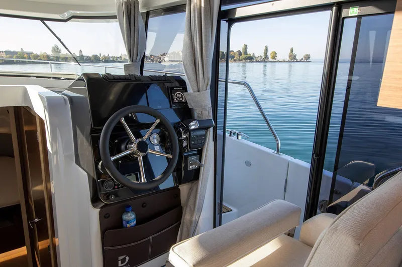 Slide: The Image of Interior view of 2025 Delphia D10 Sedan boat with steering wheel and lake view. - 13