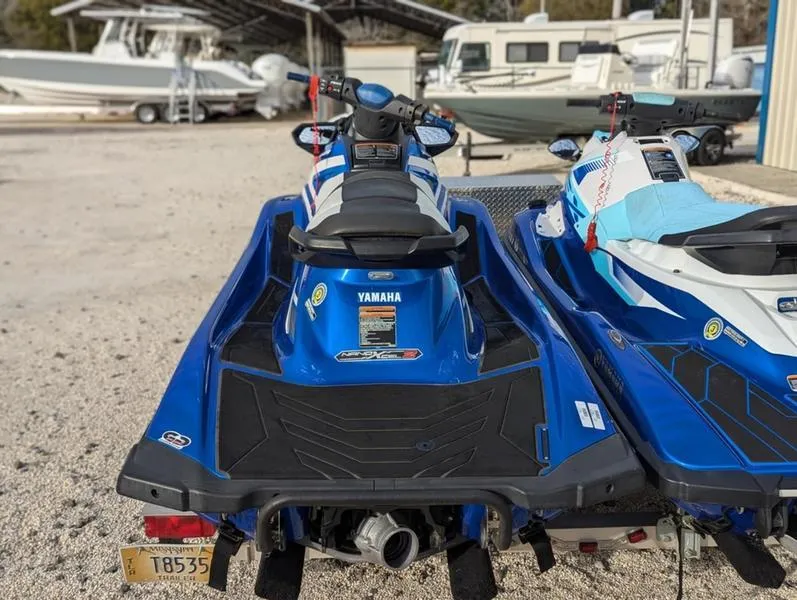 Slide: The Image of 2022 Yamaha WaveRunner EX LIMITED GP 1800 jet skis parked on gravel near boats. - 33