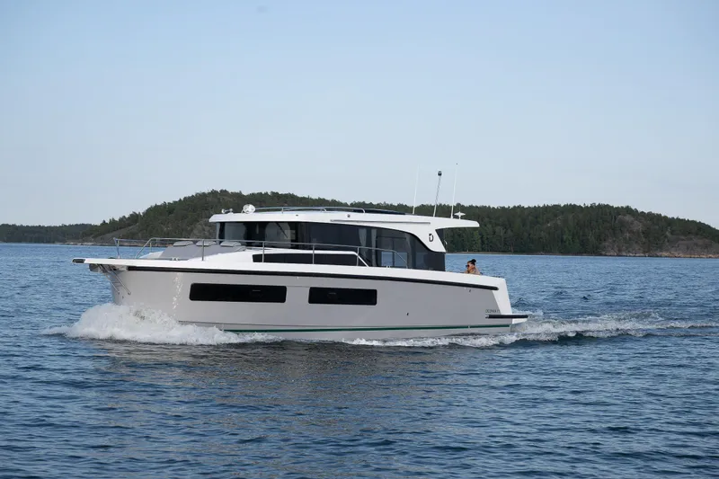 Slide: The Image of 2025 Delphia D11 SEDAN cruising on a serene lake with forested shoreline. - 1