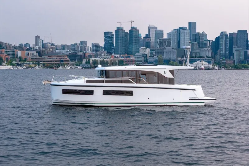 Slide: The Image of 2025 Delphia D11 SEDAN yacht cruising on water with city skyline backdrop. - 16