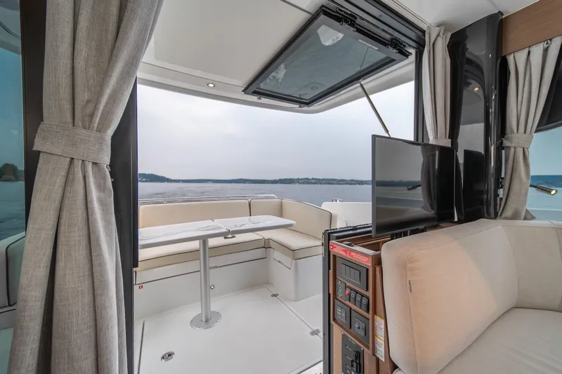 Slide: The Image of Interior of 2025 Delphia D11 SEDAN yacht with seating, table, and TV, overlooking water. - 11