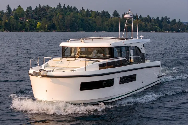 Slide: The Image of 2025 Delphia D11 SEDAN cruising on a serene lake with forested shoreline. - 14