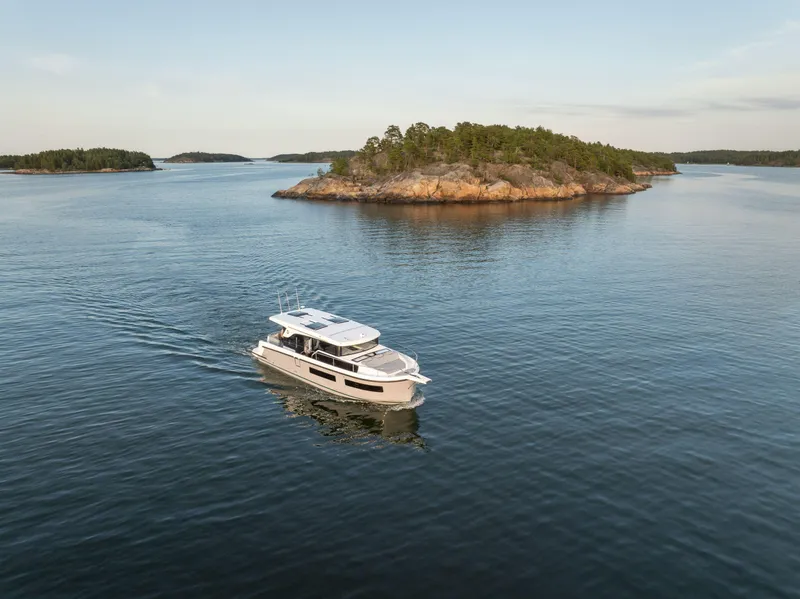 Slide: The Image of 2025 Delphia D11 SEDAN cruising near a scenic island in calm waters. - 2