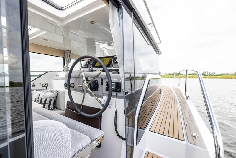 Slide: The Image of 2025 Delphia D11 SEDAN interior with steering wheel and wooden deck, overlooking water. - 4