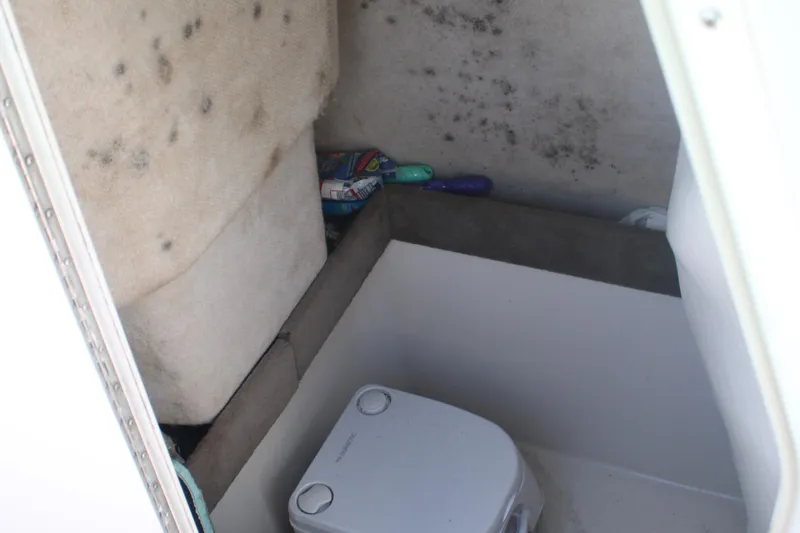 Slide: The Image of 2006 Seaswirl Striper 2601 boat cabin interior with portable toilet and storage area. - 10