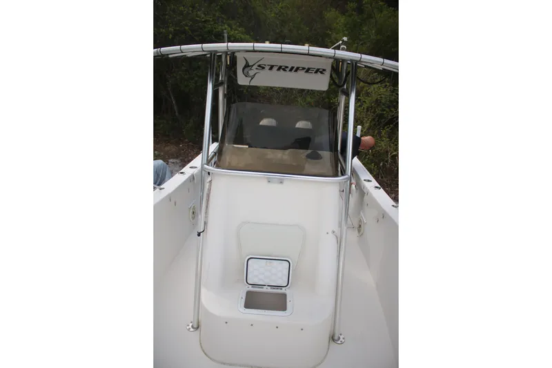 Slide: The Image of 2006 Seaswirl Striper 2601 boat with center console and canopy, docked near greenery. - 25