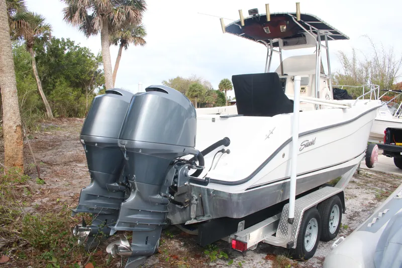 Slide: The Image of 2006 Seaswirl Striper 2601 boat on trailer with dual outboard motors, parked near palm trees. - 27