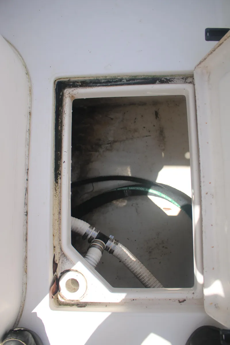 Slide: The Image of Open hatch on 2006 Seaswirl Striper 2601 boat, revealing interior compartment with hoses. - 7
