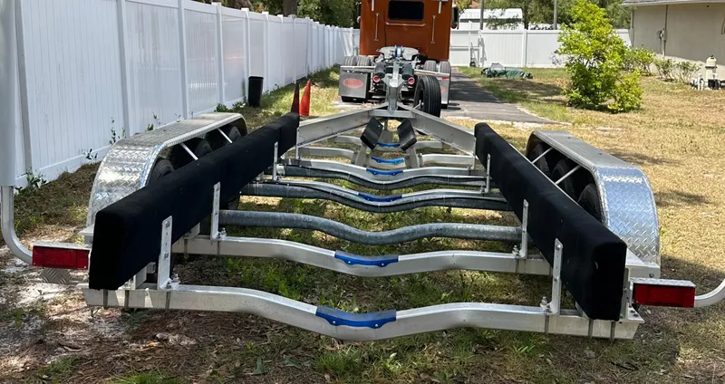 Slide: The Image of Boat trailer for 2018 Sailfish 325 DC, parked on grass near a white fence. - 22