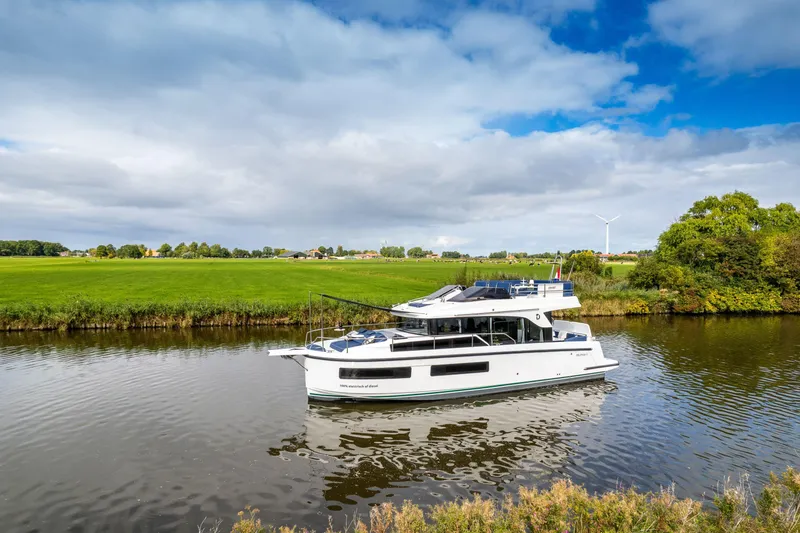 Slide: The Image of 2025 Delphia D11 Flybridge yacht cruising on a serene river with lush green surroundings. - 3