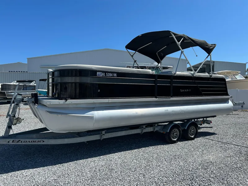 Slide: The Image of 2021 Crest 240 LX SLSC pontoon boat on trailer, parked on gravel. - 1