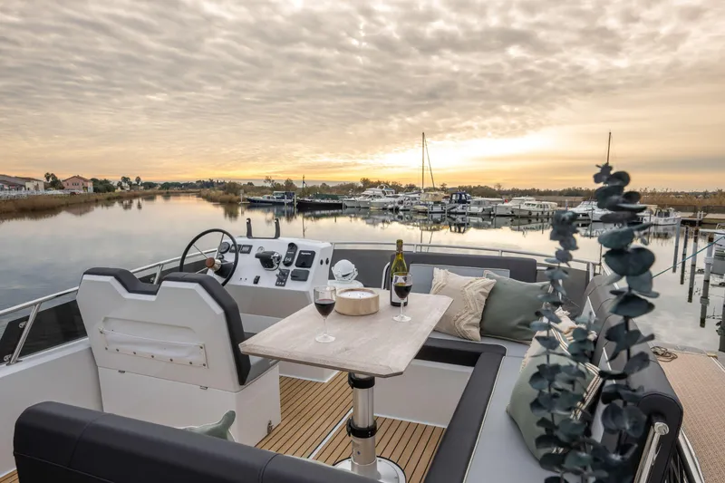 Slide: The Image of Luxurious 2025 Delphia D12 Fly yacht interior with scenic sunset view over marina. - 2