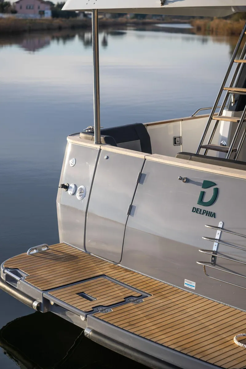Slide: The Image of 2025 Delphia D12 Fly yacht with sleek design and wooden deck, docked on calm water. - 4