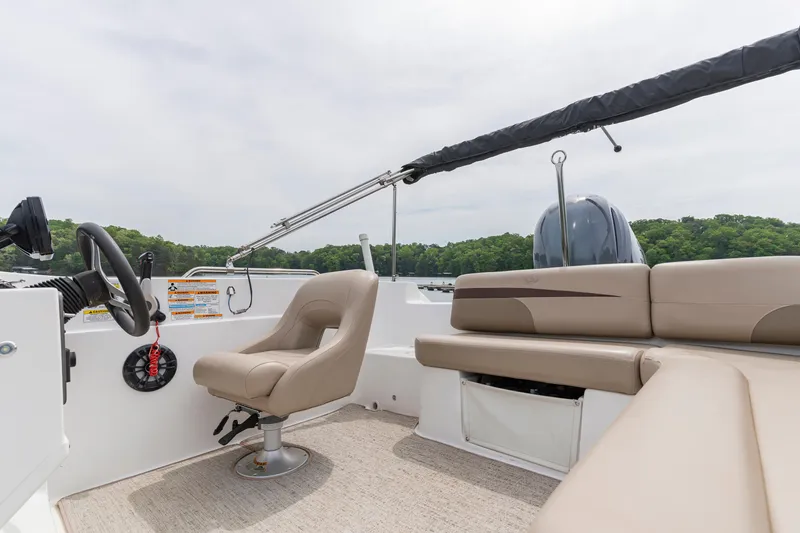 Slide: The Image of 2022 Hurricane SS201 boat interior with beige seating and steering wheel, set against a lake backdrop. - 17