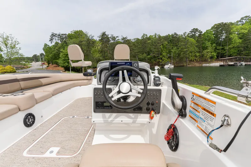 Slide: The Image of 2022 Hurricane SS201 boat interior with steering wheel, dashboard, and seating by a lake. - 3