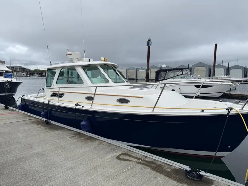 Slide: The Image of 2008 Back Cove 29 Hardback boat docked in a marina, featuring a sleek blue and white design. - 6