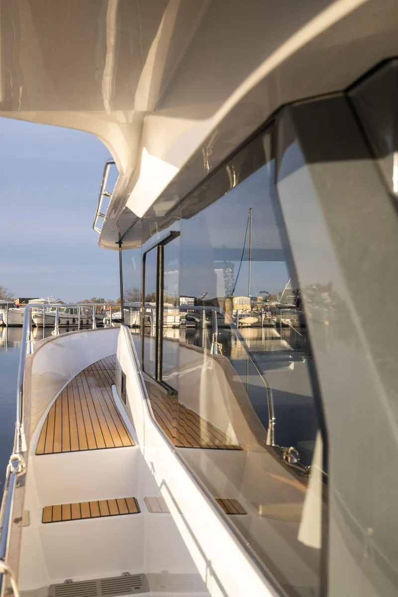 Slide: The Image of 2025 Delphia D12 Fly yacht with sleek design and wooden deck, docked at marina. - 3