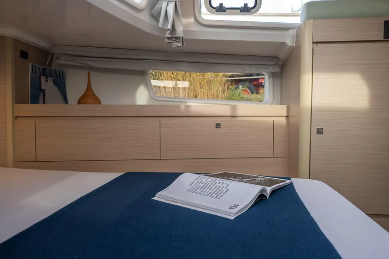 Slide: The Image of Cozy interior of 2025 Delphia D12 Fly yacht with open book on bed. - 9