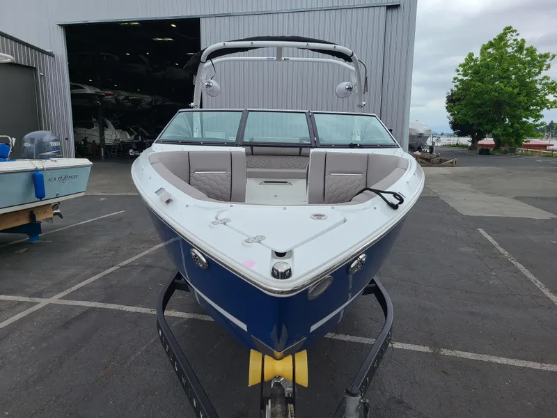 Slide: The Image of 2023 Four Winns H4 boat on trailer, parked outside a warehouse. - 2