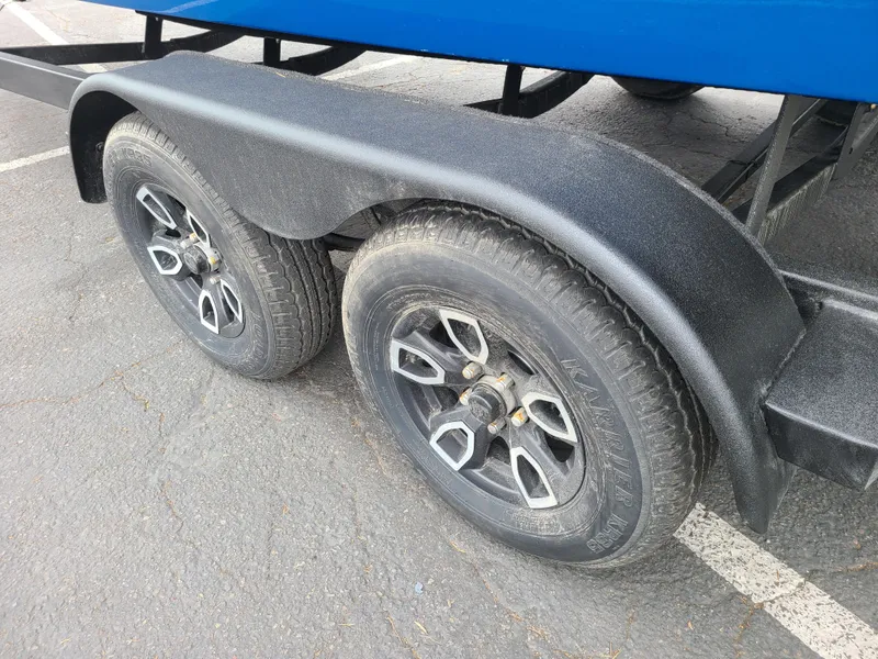 Slide: The Image of 2023 Four Winns H4 trailer with dual black wheels on asphalt. - 7