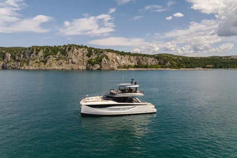 Slide: The Image of Prestige M7 yacht cruising near rocky coastline under a partly cloudy sky, 2025 model. - 24