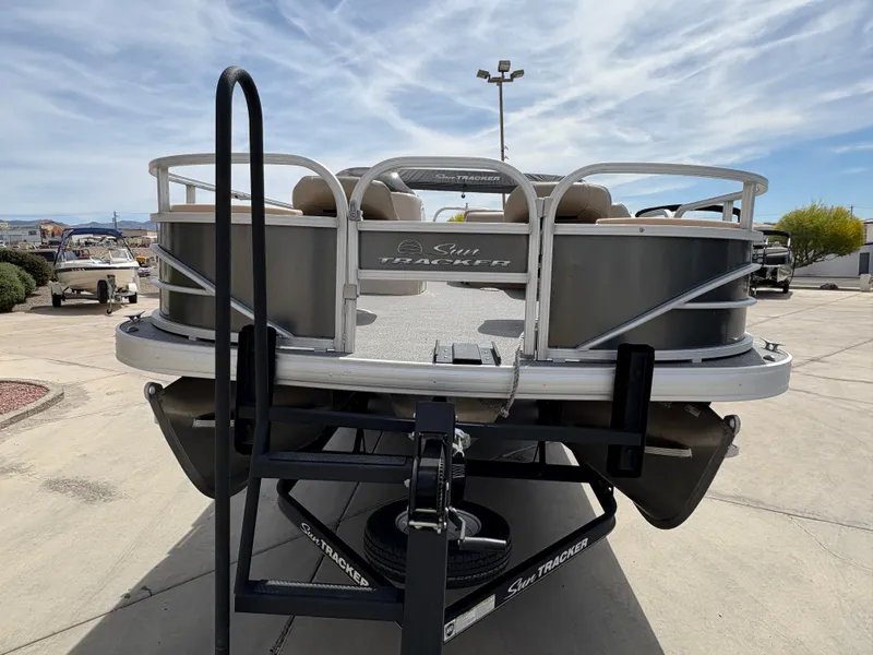 Slide: The Image of 2017 Sun Tracker Fishin' Barge 22 DLX pontoon boat on trailer, outdoor setting. - 4