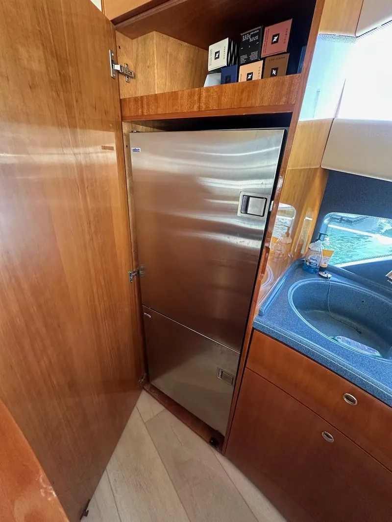 Slide: The Image of 2006 Azimut 55E yacht kitchen with stainless steel fridge and wooden cabinetry. - 9