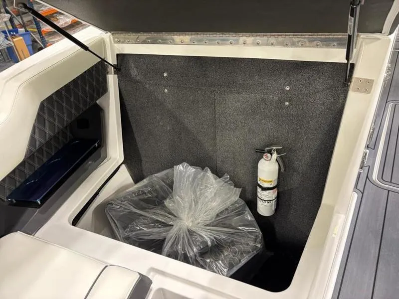 Slide: The Image of Storage compartment of 2025 Cobalt R31 boat with fire extinguisher and wrapped item. - 23