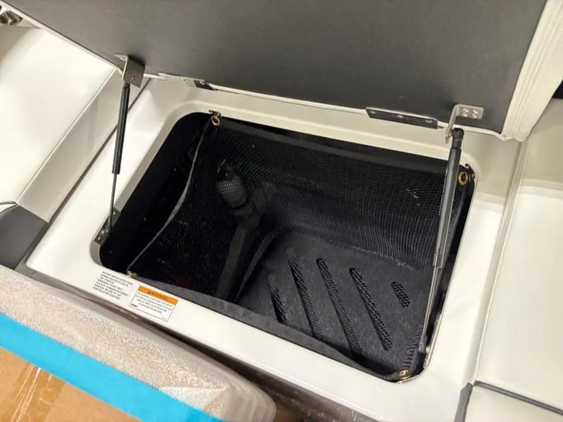 Slide: The Image of Open storage compartment in 2025 Cobalt R31 boat, featuring hydraulic hinges and black interior. - 34