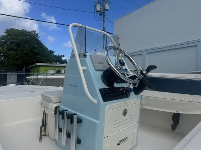 Slide: The Image of 2020 Hewes Redfisher 18 boat console with steering wheel and seating, under a clear blue sky. - 4