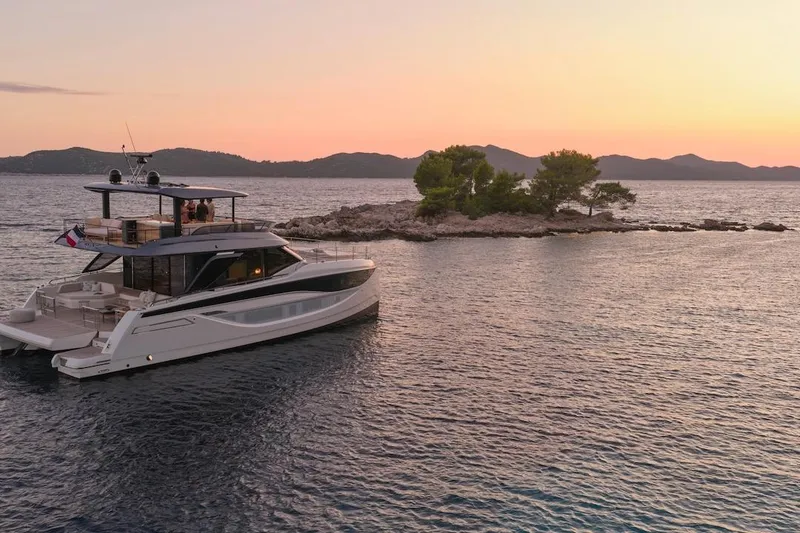 Slide: The Image of Luxury Prestige M7 yacht cruising near an island at sunset, 2025 model. - 111