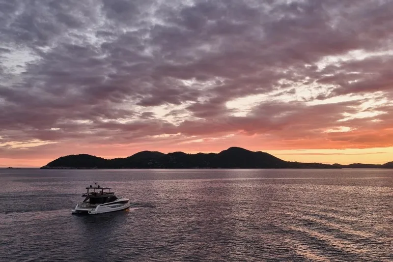 Slide: The Image of Sunset over ocean with Prestige M7 yacht, 2025 model, cruising near distant hills. - 95