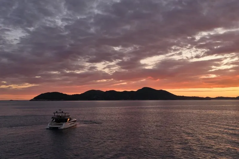 Slide: The Image of Prestige M7 yacht cruising at sunset near scenic islands, 2025 model. - 96