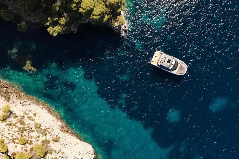 Slide: The Image of Aerial view of Prestige M7 yacht, 2025 model, near rocky coastline and clear blue waters. - 98