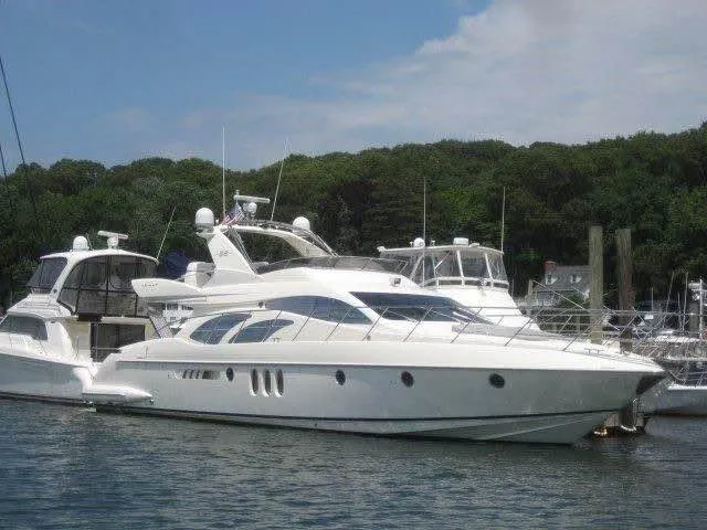 Slide: The Image of 2006 Azimut 62 yacht docked in a marina, surrounded by trees and other boats. - 1