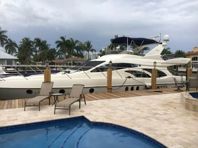 Slide: The Image of 2006 Azimut 62 yacht docked by a poolside with palm trees in the background. - 3