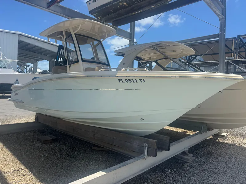 The Image of 2023 Scout 215 XSF boat on a trailer, parked outdoors under a clear blue sky. - 0