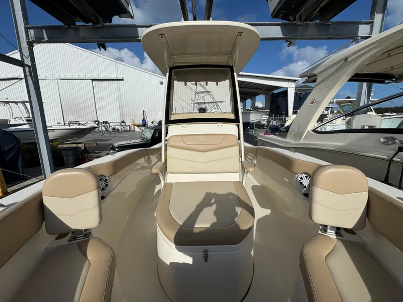 Slide: The Image of 2023 Scout 215 XSF boat interior with beige seating and console, docked under blue sky. - 7