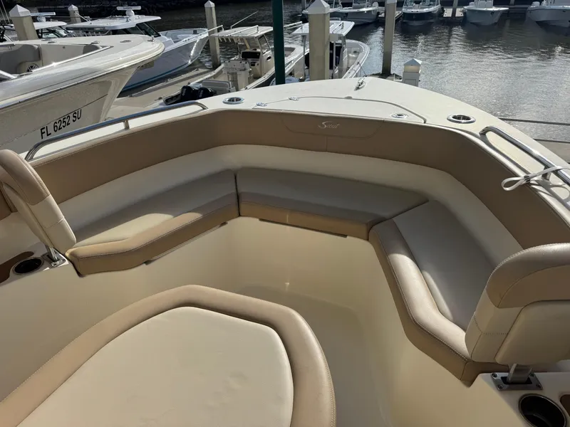 Slide: The Image of 2023 Scout 215 XSF boat interior with beige seating, docked at marina. - 8